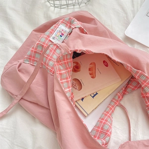 Detail of pink canvas tote bag showing green and red plaid lining and white woven label