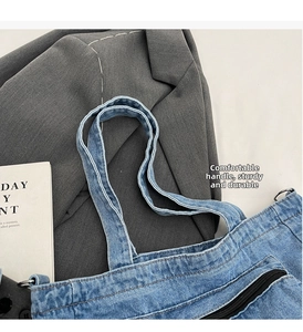 Close-up of reinforced stitching on the denim shoulder bag handles with metal zipper detail