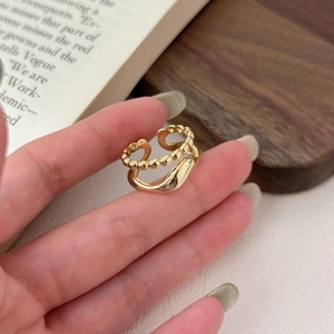 Detail of a minimalist gold layered wave ring with beaded texture worn on a hand