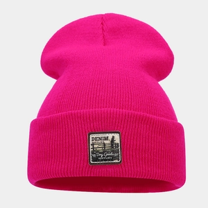 Close-up of rose red ribbed knit beanie featuring a vintage-style denim supply woven patch