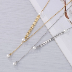 Detail view of gold and silver Y-shaped necklaces with wheat leaves and pearls