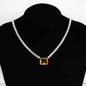 Detailed view of luxury silver necklace with large yellow gemstone on black bust model