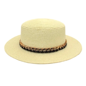 Détail d'un chapeau canotier crème avec chaîne dorée et ruban noir pour protection solaire