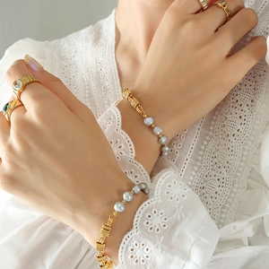 Elegant gold chain bracelet featuring grey freshwater pearls on model wrist