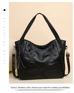 Detail view of black textured tote bag featuring woven handles and leather tassel accent