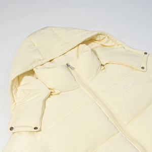 Detail of a creamy yellow hooded puffer jacket with a zipper and metal snap buttons