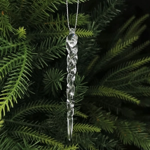 Macro shot of clear acrylic icicle ornament with spiral texture hanging on pine branch