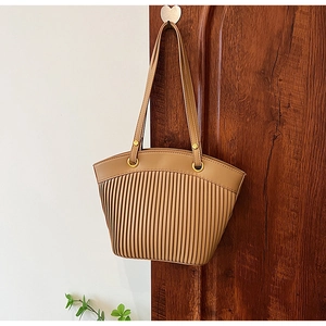 Detail of vertical pleated texture and metal ring buckle on khaki straw shoulder bag