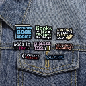 Set of 8 colorful enamel reading book badges pinned on a blue denim jacket pocket