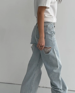 Vue latérale du jean droit bleu clair avec genou déchiré et coupe large décontractée