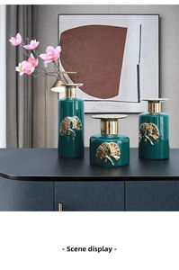 Detailed close-up of emerald green ceramic vases with elegant gold ginkgo leaf relief motifs