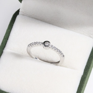 Macro shot of silver adjustable letter ring with diamonds in a green jewelry gift box