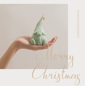 Close-up of a green Santa Gnome scented candle with a gold heart detail and Merry Christmas text