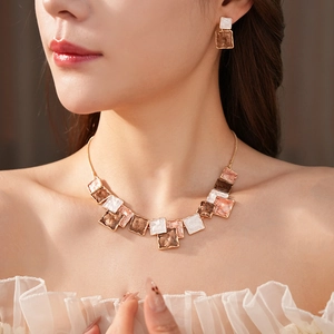 Close-up of elegant gold square enamel jewelry set worn by a model in soft lighting