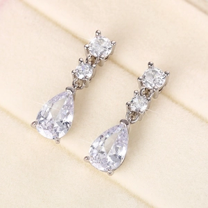 Macro shot of silver teardrop earrings with luxury pear-shaped zirconia on velvet pad