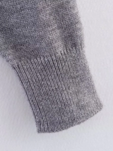 Close-up of classic ribbed knit cuffs on a grey short cardigan made of soft wool blend
