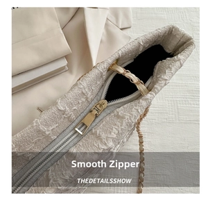 Close-up of high-quality smooth zipper and elegant chain on beige textured tote bag