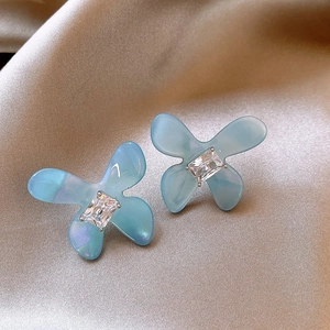 Close-up of vintage enamel floral earrings with blue resin petals and central crystal detail