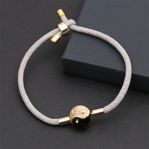 Detail of adjustable gray Milan rope bracelet with Tai Chi Yin Yang charm and gold accents