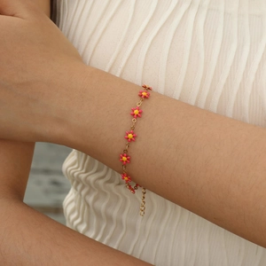 Close-up of golden chain bracelet featuring pink drip oil flower petals on a wrist