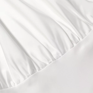 Détail du tissu en satin blanc montrant le plissage délicat et la texture soyeuse