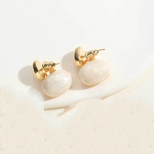 Detail of 14K gold plated earrings with white oval faux pearls and spiral sand textures