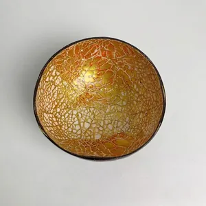 Detail view of handmade coconut shell bowl with decorative gold and orange mosaic interior