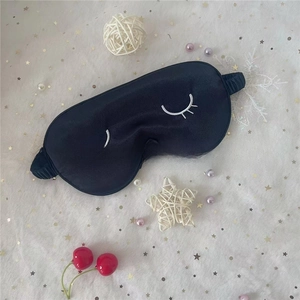 Detail of black silk sleep mask featuring white eyelash embroidery and elastic headband