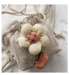 Dettaglio borsa a secchiello in paglia beige con decorazioni floreali in tessuto 3D