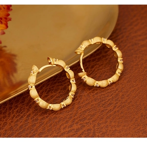 Detail of vintage matte gold hoop earrings with sparkling cubic zirconia on leather