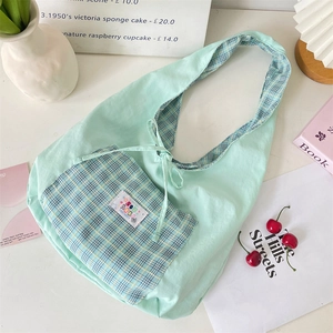 Detail of light mint green canvas tote with a plaid pocket and decorative solar patch