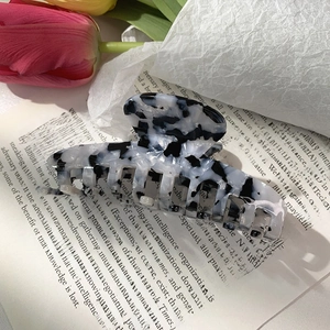 Detail of black and white marble acetate hair claw clip with floral background