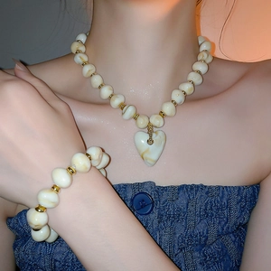 Detailed shot of cream marble acrylic heart necklace and bracelet set with gold beads