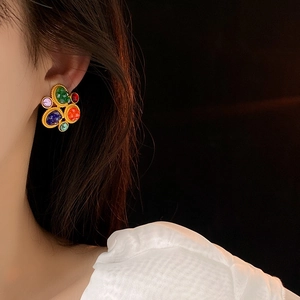 Close-up of vintage gold floral earrings with colorful gemstones on a female model