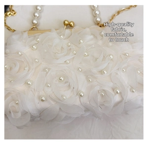Détails des pétales de rose en mousseline 3D et perles sur une pochette blanche