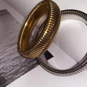 Dettaglio di bracciali tubogas oro e argento con texture metallica a coste e lucida