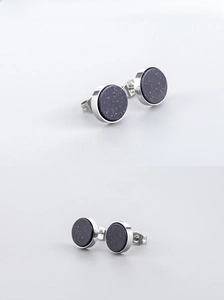 Detailed close-up of punk style round earrings with sparkling blue sandstone in silver steel