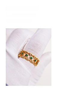 Detailed macro of vintage emerald zircon ring with intricate gold lace openwork