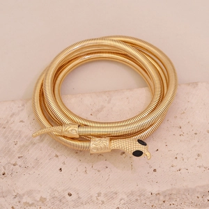 Dettaglio di un bracciale a serpente dorato con trama a scaglie e piccoli occhi neri