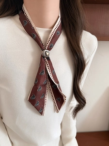 Close-up of brown paisley silk scarf with heart-shaped metal buckle on model neck