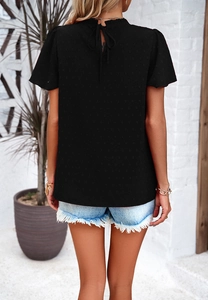 Detail of black short sleeve top with lace trim and back tie closure on textured fabric