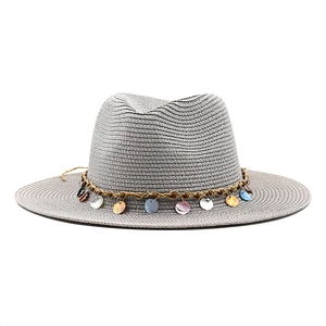 Detail of grey fedora straw hat featuring colorful shell pendants on a brown woven band