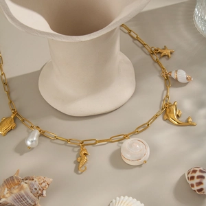Détail du collier marin doré avec des breloques étoile de mer, hippocampe et perle