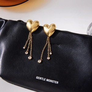 Detail of heart stud earrings with golden tassel chains and sparkling zircon stones