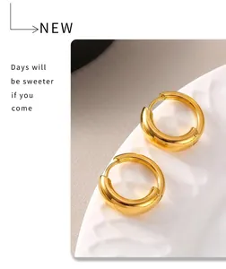 Close-up of polished 18k gold plated hoop earrings on white ceramic tray