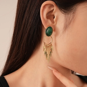 Vintage oval green resin earrings with hanging gold metal fringe on a model
