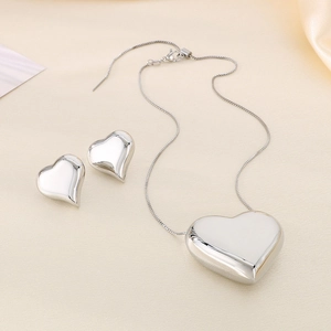 Parure collier et boucles d'oreilles cœur en argent poli sur tissu de soie