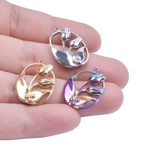 Three tulip flower pendants in gold, silver, and rainbow colors held by hand for jewelry DIY