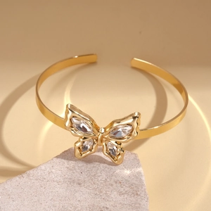 Close-up of golden butterfly arm cuff featuring sparkling crystals on polished metal