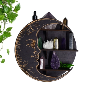Detail of dark wood crescent moon shelf with carved face and tiered shelves for crystals